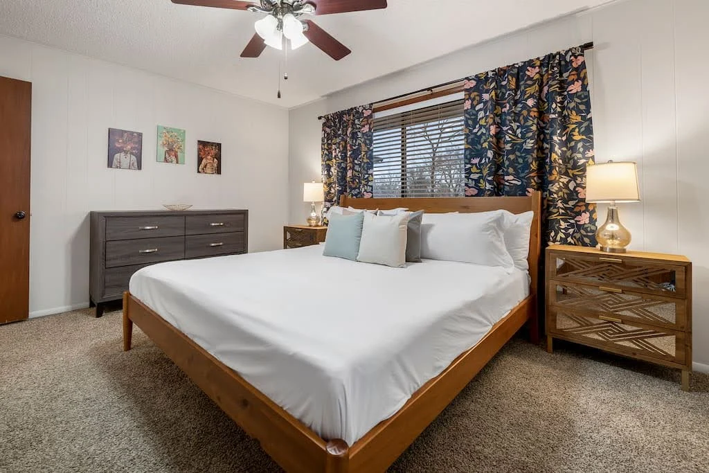 Vintage-inspired Airbnb bedroom with a wood bed, patterned curtains, and antique-style furniture