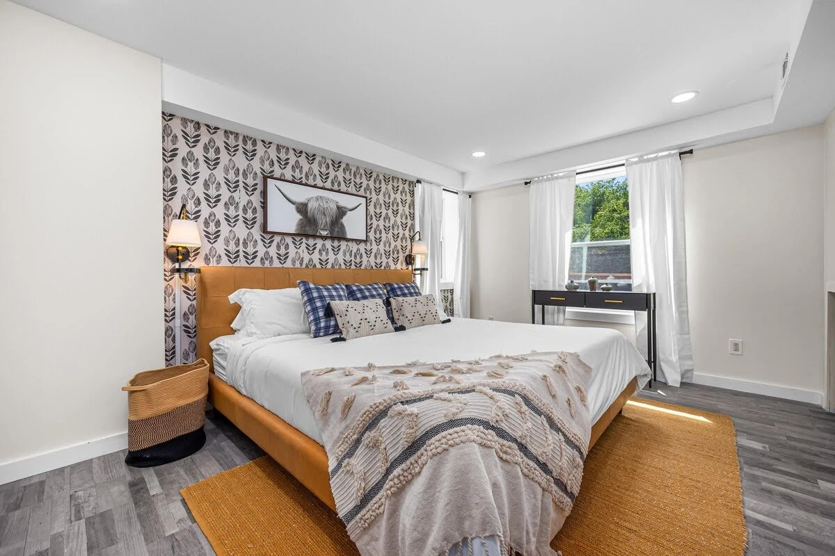 Modern farmhouse Airbnb bedroom with a black patterned wall and wood furniture