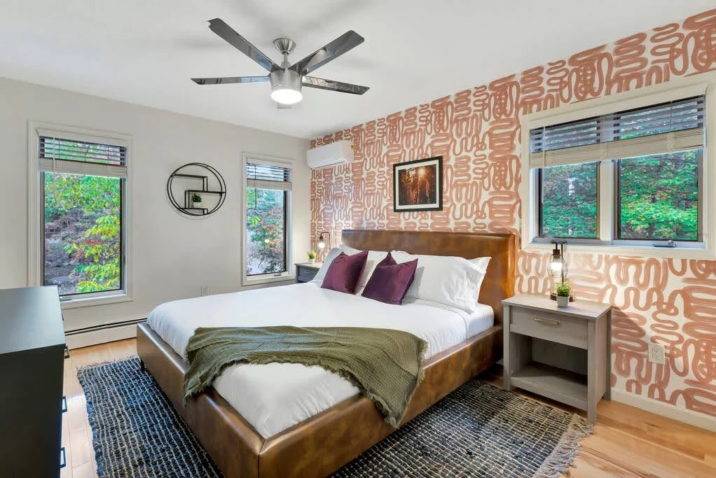 Airbnb bedroom with layered patterns, warm wood furniture, and a green bed frame