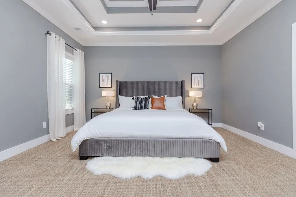 Gray Airbnb bedroom with a centered upholstered bed and matching bedside tables