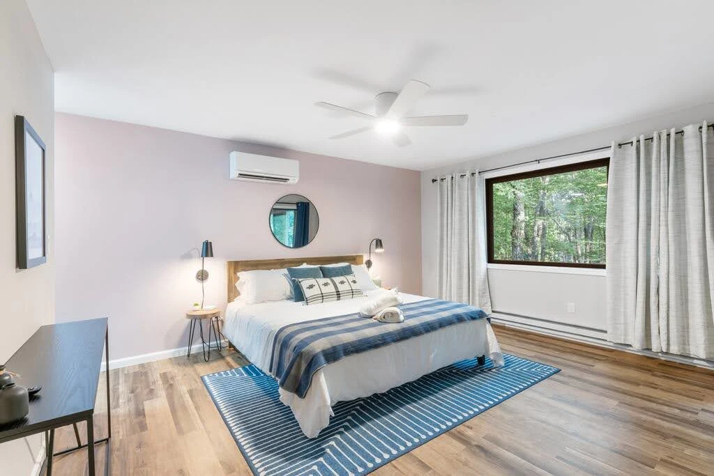 White and blue Airbnb bedroom with a striped rug and compact bedside tables