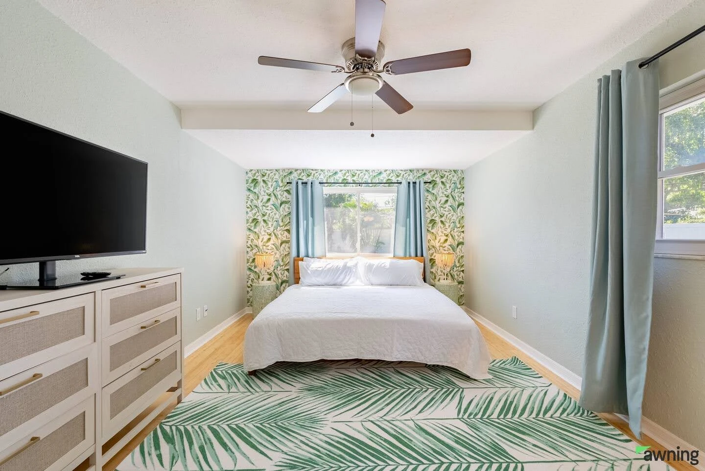 Airbnb bedroom with floral wallpaper, a white bed, and a green patterned rug