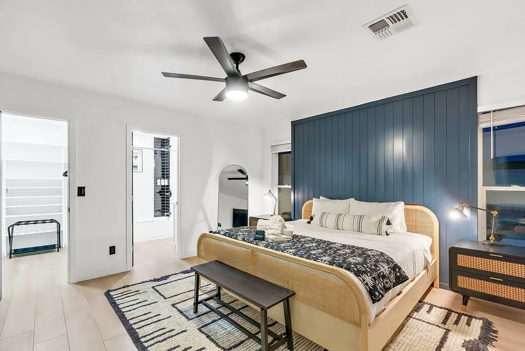 Comfortable Airbnb bedroom with a dark feature wall, bench, rug, and upholstered bed