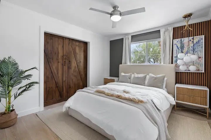 Mid-century Airbnb bedroom with a wood accent wall, low bed, and large window